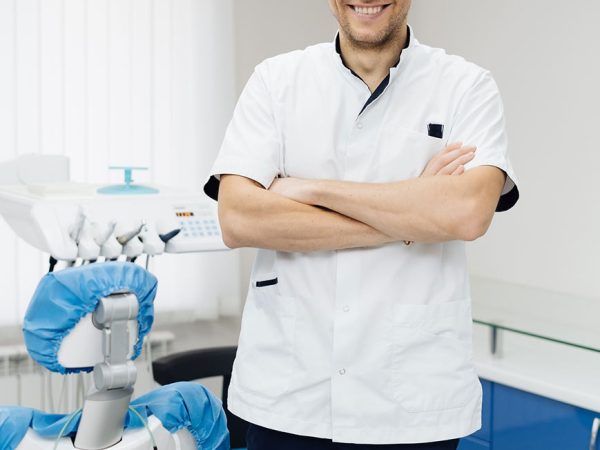 retrato-de-un-denti4sta-masculino-joven-positivo-en-uniforme-con-las-manos-cruzadas-en-el-consultorio-dental retrato-de-un-denti4sta-masculino-joven-positivo-en-uniforme-con-las-manos-cruzadas-en-el-consultorio-dental